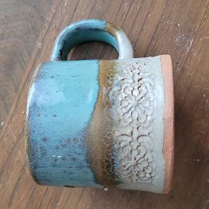 Hand thrown pottery mug with floral stamp detailing blue and green glaze